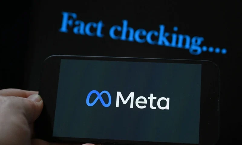 This photo illustration created on January 8, 2025, in Brussels, shows the media giant Meta's logo displayed on a smartphone and screen displaying the words "fact checking". Social media giant Meta on January 7, 2025, slashed its content moderation policies, including ending its US fact-checking program, in a major shift that conforms with the priorities of incoming president Donald Trump. (Photo by Nicolas TUCAT / AFP) (Photo by NICOLAS TUCAT/AFP via Getty Images)