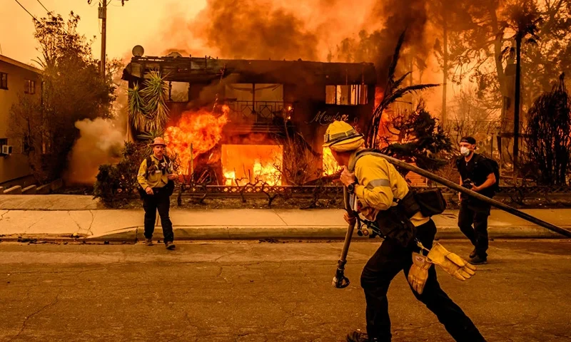 TOPSHOT - Firefighters work the scene as an apartment building burns during the Eaton fire in the Altadena area of Los Angeles county, California on January 8, 2025. At least five people are now known to have died in wildfires raging around Los Angeles, with more deaths feared, law enforcement said January 8, as terrifying blazes leveled whole streets, torching cars and houses in minutes. More than 1,000 buildings have burned in multiple wildfires that have erupted around America's second biggest city, forcing tens of thousands of people from their homes. (Photo by JOSH EDELSON / AFP) (Photo by JOSH EDELSON/AFP via Getty Images)