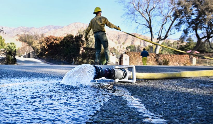 TOPSHOT - Water flows out of a hose as a firefighter pulls another hose on January 13, 2025 in Altadena, California. Homeowners and renters who lost their homes due to the fire are suing Southern California Edison, alleging the electrical utility that provides electricity to some 15 million people in a 50,000 square-mile area of Southern California failed to de-energize its electrical equipment despite the high wind and red flag warnings issues by the National Weather Service. (Photo by Frederic J. BROWN / AFP) (Photo by FREDERIC J. BROWN/AFP via Getty Images)