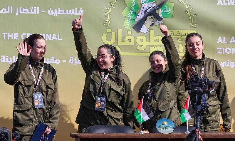 Four Israeli hostages, (L-R) Naama Levy, Liri Albag, Daniella Gilboa and Karina Ariev, wave on a stage before Hamas fighters hand them over to a team from the Red Cross in Gaza City on January 25, 2025. Hamas militants handed over four Israeli women hostages to the Red Cross in a January 25 swap after parading them on a stage at a square in Gaza, an AFP journalist reported. (Photo by Omar AL-QATTAA / AFP) (Photo by OMAR AL-QATTAA/AFP via Getty Images)