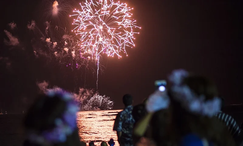 People watch a New Year's fireworks display on Waikiki beach on January 1, 2015. President Barack Obama -- still on vacation in Hawaii -- plans to spend New Year's eve with loved ones "at home," the White House said. AFP PHOTO / NICHOLAS KAMM (Photo credit should read NICHOLAS KAMM/AFP via Getty Images)