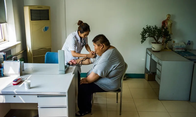 TOPSHOT - This picture taken on May 25, 2015 shows a nurse taking the blood pressure of an overweight boy during his acupuncture and exercise treatment at the Aimin (Love the People) Fat Reduction Hospital in the northern port city of Tianjin. AFP PHOTO / FRED DUFOUR (Photo by FRED DUFOUR / AFP) (Photo by FRED DUFOUR/AFP via Getty Images)