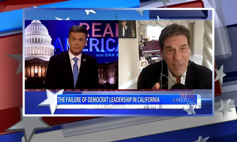 Video still from Real America on One America News Network showing a split screen of the host on the left side, and on the right side is the guest, Robert Davi.