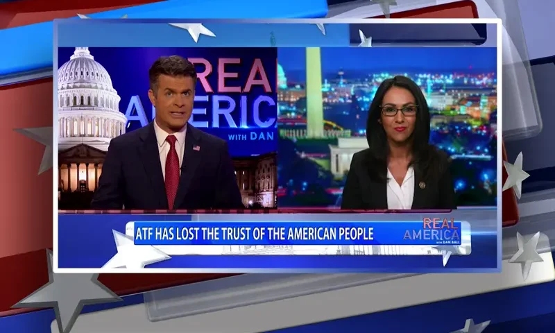 Video still from Real America on One America News Network showing a split screen of the host on the left side, and on the right side is the guest, Rep. Lauren Boebert.
