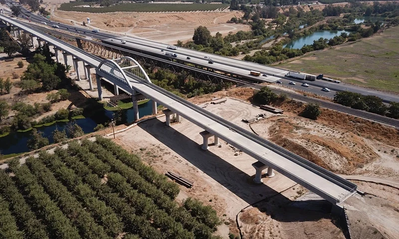 In this aerial image taken on August 26, 2021 vehicles drive past farmland and part of the California High Speed Rail Authority San Joaquin River viaduct construction project alongside US Highway 99 through the Central Valley between Madera County and Fresno County, California. - The US Senate passed a bipartisan infrastructure development bill that would see a $1.2 trillion investment in roads, bridges, water pipes and high-speed internet across the United States. (Photo by Patrick T. FALLON / AFP) (Photo by PATRICK T. FALLON/AFP via Getty Images)