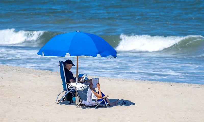 TOPSHOT - US President Joe Biden (L) and US First Lady Jill Biden sit under an umbrella in Rehoboth Beach, Delaware, on July 30, 2023. (Photo by Jim WATSON / AFP) (Photo by JIM WATSON/AFP via Getty Images)
