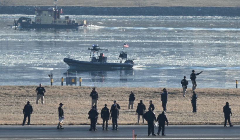 People, including law enforcement members, are seen on a runway at Ronald Reagan Washington National Airport