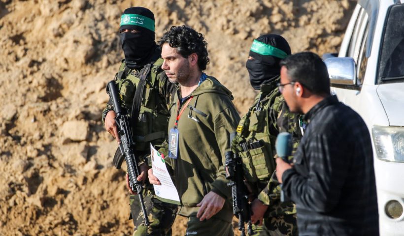 TOPSHOT - Palestinian militant group Hamas fighters escort Israeli-French hostage Ofer Kalderon before handing him over to a Red Cross team in Khan Yunis on February 1, 2025, as part of fourth hostage-prisoner exchange. (Photo by Eyad BABA / AFP) (Photo by EYAD BABA/AFP via Getty Images)