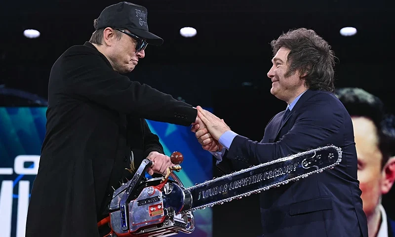 TOPSHOT - Billionaire Elon Musk, the head of the Department of Government Efficiency (DOGE), holds a chainsaw reading "Long live freedom, damn it" as he shakes hands with Argentinian President Javier Milei at the annual Conservative Political Action Conference (CPAC). (Photo by SAUL LOEB / AFP) (Photo by SAUL LOEB/AFP via Getty Images)