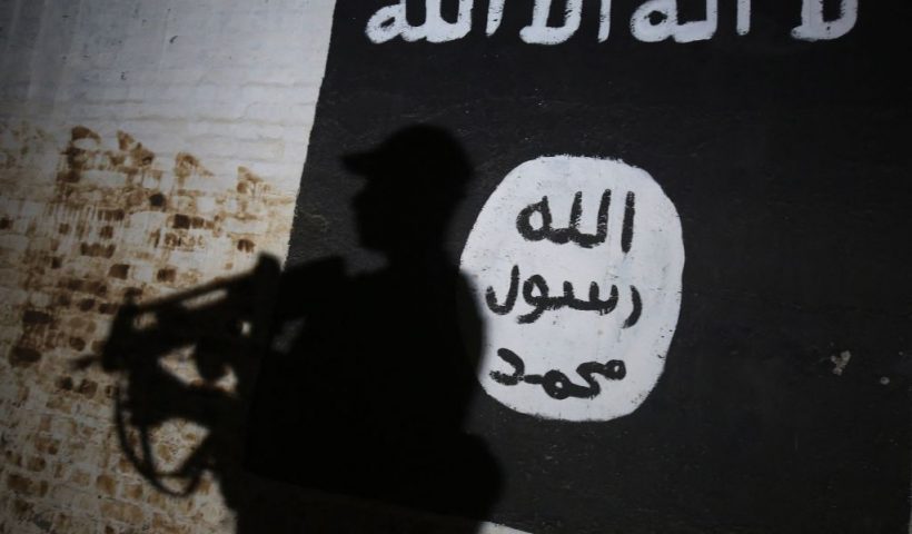 TOPSHOT - A member of the Iraqi forces walks past a mural bearing the logo of the Islamic State (IS) group in a tunnel that was reportedly used as a training centre by the jihadists, on March 1, 2017, in the village of Albu Sayf, on the southern outskirts of Mosul. Iraqi forces launched a major push on February 19 to recapture the west of Mosul from the Islamic State jihadist group, retaking the airport and then advancing north. (Photo by AHMAD AL-RUBAYE / AFP) (Photo by AHMAD AL-RUBAYE/AFP via Getty Images)