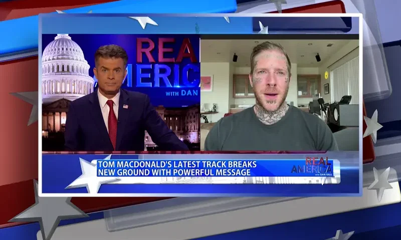 Video still from Real America on One America News Network showing a split screen of the host on the left side, and on the right side is the guest, Tom MacDonald.