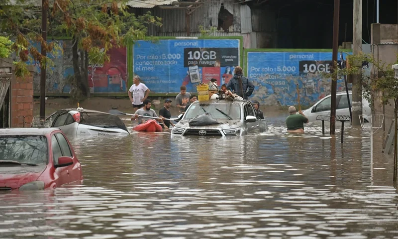 People gather on a flooded street after a powerful storm struck the city of Bahia Blanca, 600 km south of Argentina's capital, on March 7, 2025. Six people died and hundreds were evacuated in the Argentine port city of Bahia Blanca as torrential rains flooded homes and hospitals, destroyed roads and forced authorities to cut the power. (Photo by PABLO PRESTI / AFP) (Photo by PABLO PRESTI/AFP via Getty Images)