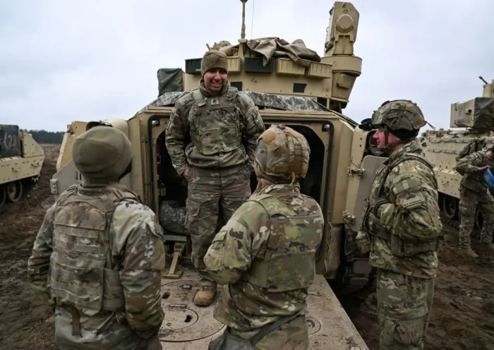 DRAWSKO POMORSKIE, POLAND - MARCH 13: Soldiers of the US Army 3rd Brigade, 1st Armored Division speak next to a Bradley Fighting Vehicle ahead of a live fire exercise at the Drawsko Pomorskie training area on March 13, 2025 in Drawsko Pomorskie, Poland. Poland has historically been one of America's closest European allies, currently hosting approximately 10,000 members of the US Armed Forces, who play a significant role in reinforcing security along NATO's eastern flank. Recently, however, the United States' ongoing military presence in Europe has been cast into doubt, as US President Donald Trump pressures NATO member states to increase their defence spending, and to decrease their reliance on America for its military funding and resources. (Photo by Omar Marques/Getty Images)