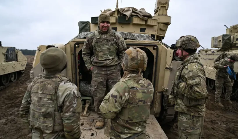 DRAWSKO POMORSKIE, POLAND - MARCH 13: Soldiers of the US Army 3rd Brigade, 1st Armored Division speak next to a Bradley Fighting Vehicle ahead of a live fire exercise at the Drawsko Pomorskie training area on March 13, 2025 in Drawsko Pomorskie, Poland. Poland has historically been one of America's closest European allies, currently hosting approximately 10,000 members of the US Armed Forces, who play a significant role in reinforcing security along NATO's eastern flank. Recently, however, the United States' ongoing military presence in Europe has been cast into doubt, as US President Donald Trump pressures NATO member states to increase their defence spending, and to decrease their reliance on America for its military funding and resources. (Photo by Omar Marques/Getty Images)
