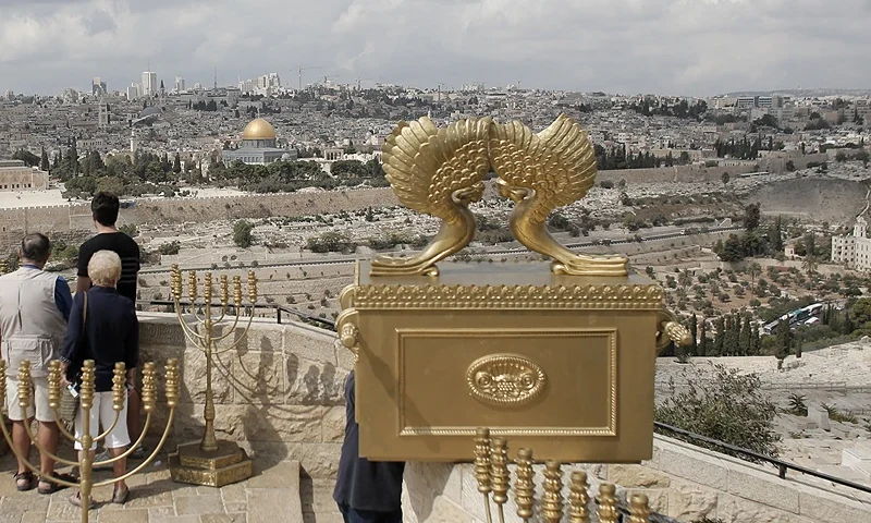 Tourists stand on October 16, 2014 at the Mount of Olives, overlooking the Al-Aqsa mosque compound, in Jerusalem's Old City next to a model of the Ark of the Covenant. This was a chest decribed in the Book of Exodus which contained the stone tablets on which the Ten Commandments were inscribed and kept in the Jewish temple of King Solomon until its destruction by the Babylonians in 597 BC. The compound, a flashpoint because of its significance to both Muslims and Jews, is known as Al-Haram Al-Sharif (Noble Sancuary) to Muslims and houses the mosque, Islam's third holiest shrine. The compound is also the traditional site of the temple of Solomon and the later temple of Herod and parts of it are holy to the Jews who refer to it as the Temple Mount. AFP PHOTO/AHMAD GHARABLI (Photo credit should read AHMAD GHARABLI/AFP via Getty Images)
