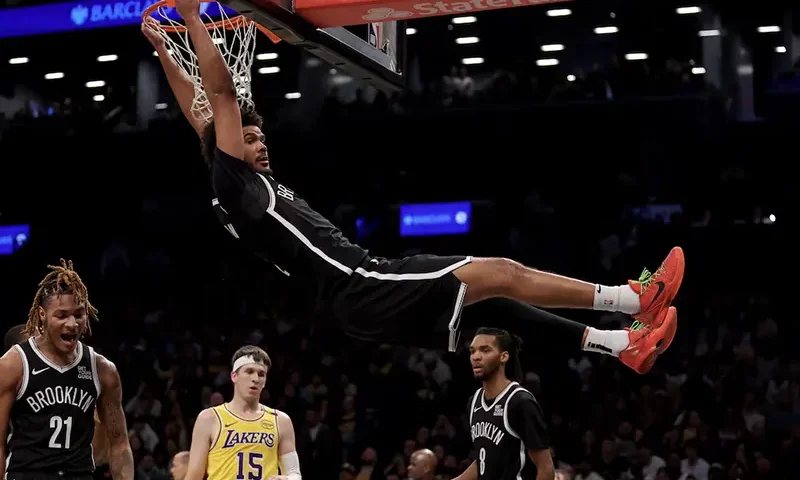 Brooklyn Nets forward Cameron Johnson (2) hangs on the rim after a dunk against the Los Angeles Lakers during the fourth quarter at Barclays Center. Mandatory Credit: Brad Penner-Imagn Images