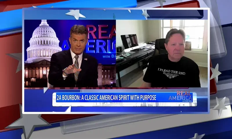 Video still from Real America on One America News Network showing a split screen of the host on the left side, and on the right side is the guest, Tim Oates.