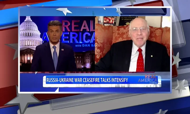 Video still from Real America on One America News Network showing a split screen of the host on the left side, and on the right side is the guest, Lt. Col. Robert Maginnis.