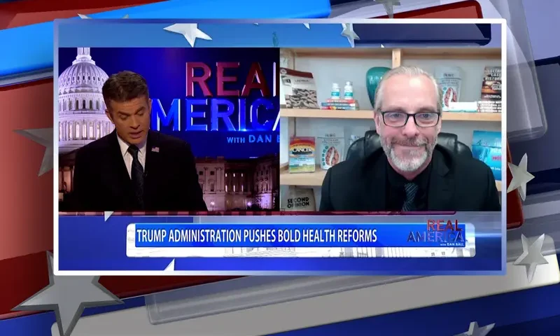 Video still from Real America on One America News Network showing a split screen of the host on the left side, and on the right side is the guest, Dr. John Richardson.