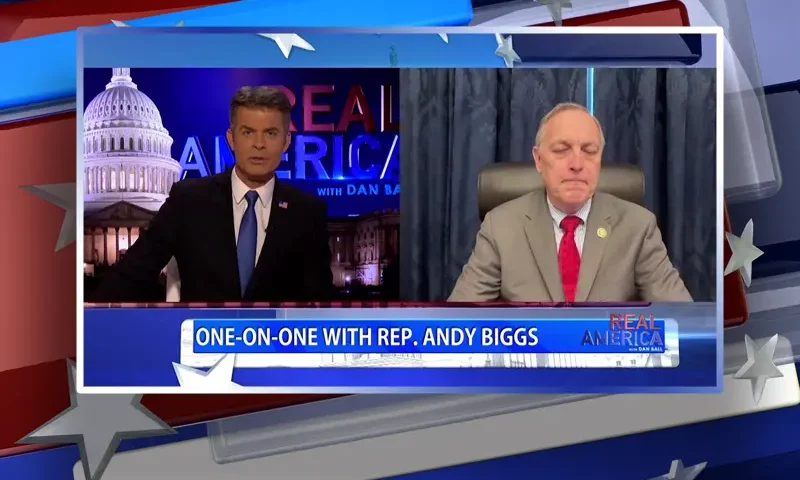 Video still from Real America on One America News Network showing a split screen of the host on the left side, and on the right side is the guest, Rep. Andy Biggs.
