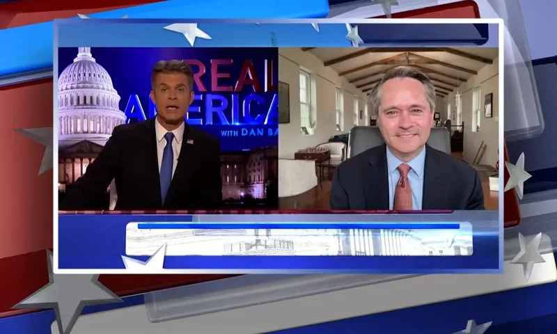 Video still from Real America on One America News Network showing a split screen of the host on the left side, and on the right side is the guest, John Hart.
