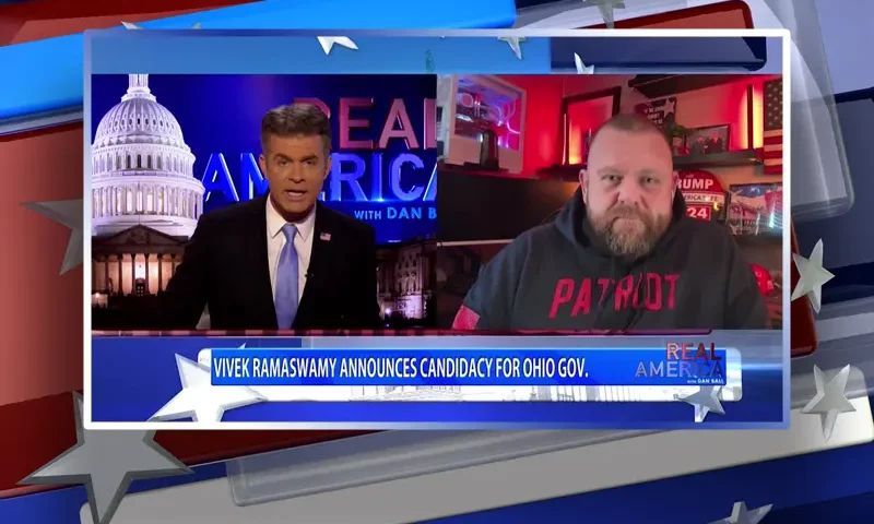 Video still from Real America on One America News Network showing a split screen of the host on the left side, and on the right side is the guest, JR Majewski.