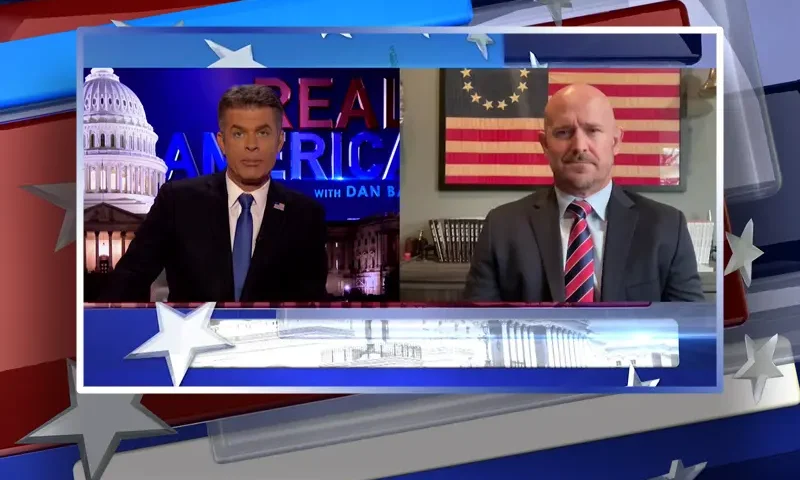 Video still from Real America on One America News Network showing a split screen of the host on the left side, and on the right side is the guest, Mike Sarraille.