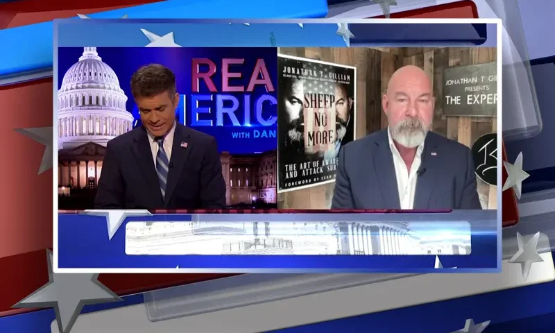 Video still from Real America on One America News Network showing a split screen of the host on the left side, and on the right side is the guest, Jonathan Gilliam.