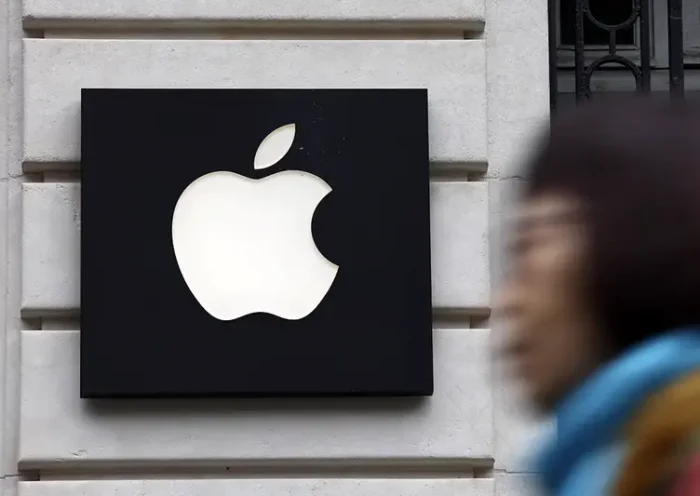 A woman walks past an Apple logo at an Apple store in Paris, France, April 23, 2025. REUTERS/Abdul Saboor