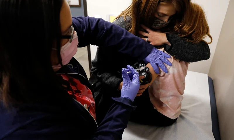 A 6 year-old child is comforted by her mother as she receives her first dose of the Pfizer-BioNTech Covid-19 vaccine by medical assistant Alli Shapiro at the Child Health Associates office in Novi, Michigan on November 3, 2021. An expert panel unanimously recommended Pfizer-BioNTech's Covid vaccine for five- to 11-year-olds on November 2, the penultimate step in the process that will allow injections in young children to begin this week in the United States. The Centers for Disease Control and Prevention (CDC), the top US public health agency, was expected to endorse that recommendation later in the day. (Photo by JEFF KOWALSKY / AFP) (Photo by JEFF KOWALSKY/AFP via Getty Images)
