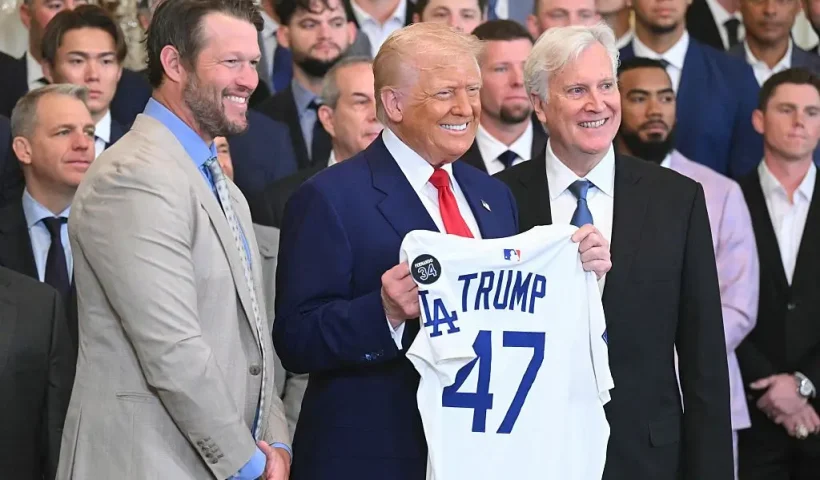 TOPSHOT - US President Donald Trump holds up a jersey alongside pitcher Clayton Kershaw (L) and team owner Mark Walter (R) during an event honoring the 2024 World Series champions Los Angeles Dodgers in the East Room of the White House in Washington, DC, on April 7, 2025. (Photo by SAUL LOEB / AFP) (Photo by SAUL LOEB/AFP via Getty Images)