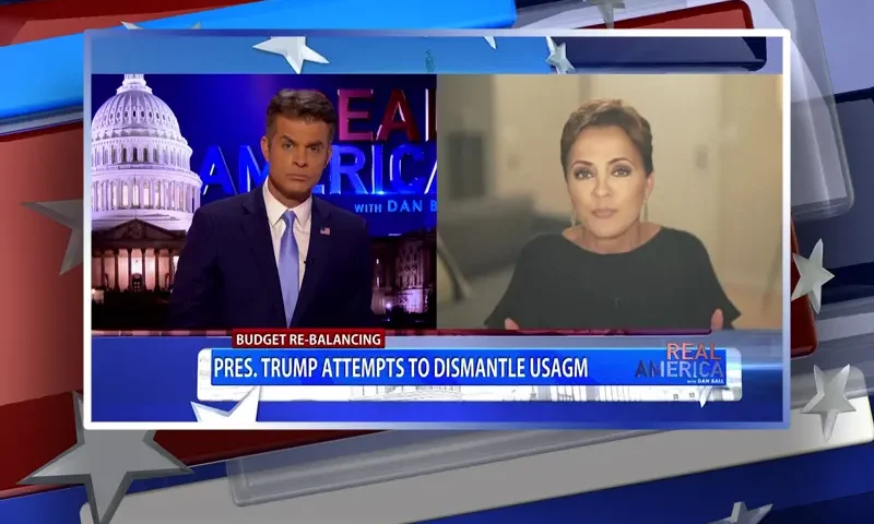 Video still from Real America on One America News Network showing a split screen of the host on the left side, and on the right side is the guest, Kari Lake.