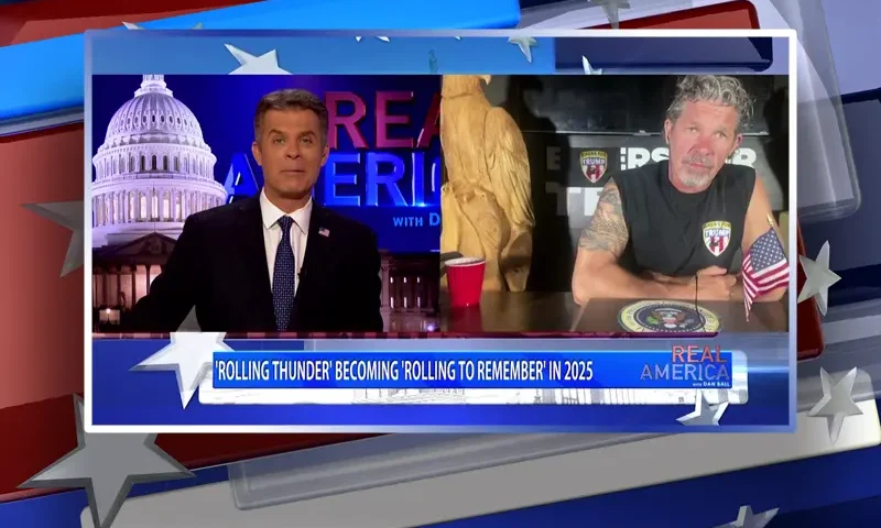 Video still from Real America on One America News Network showing a split screen of the host on the left side, and on the right side is the guest, Chris Cox.