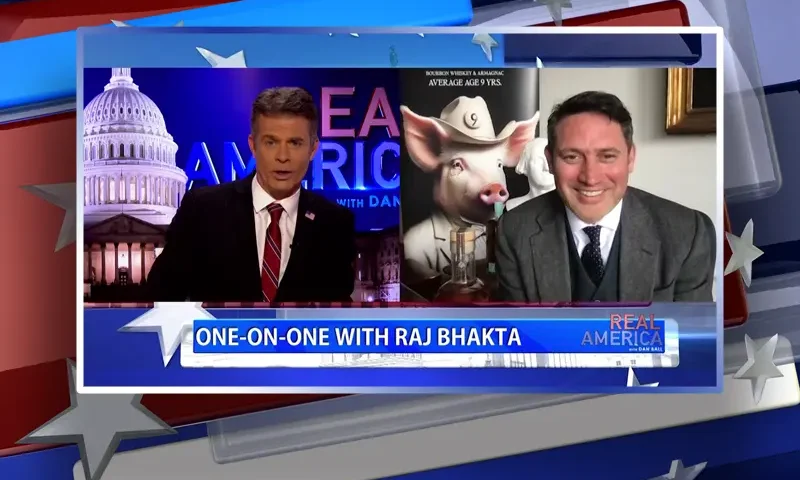 Video still from Real America on One America News Network showing a split screen of the host on the left side, and on the right side is the guest, Raj Bhakta.