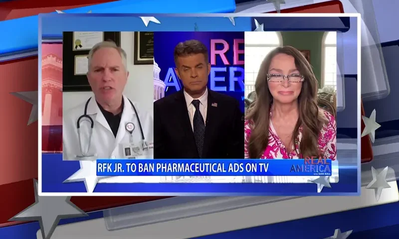 Video still from Real America on One America News Network showing a split screen of the host on and the guests, Richard Bartlett and Charlene Bollinger.