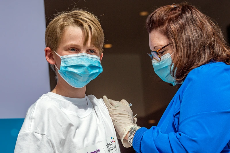 Charles Muro,age 13, is inoculated by a Nurse at Hartford Healthcare's mass vaccination center at the Connecticut Convention Center in Hartford, Connecticut on May 13, 2021. Six Children were vaccinated at the site and joined other children in the United States as kids ages 12-15 are now able to be vaccinated with the Pfizer-BioNTech Covid-19 vaccine, joining the growing population of the US that can be vaccinated against the Covid-19 virus. (Photo by Joseph Prezioso / AFP) (Photo by JOSEPH PREZIOSO/AFP via Getty Images)