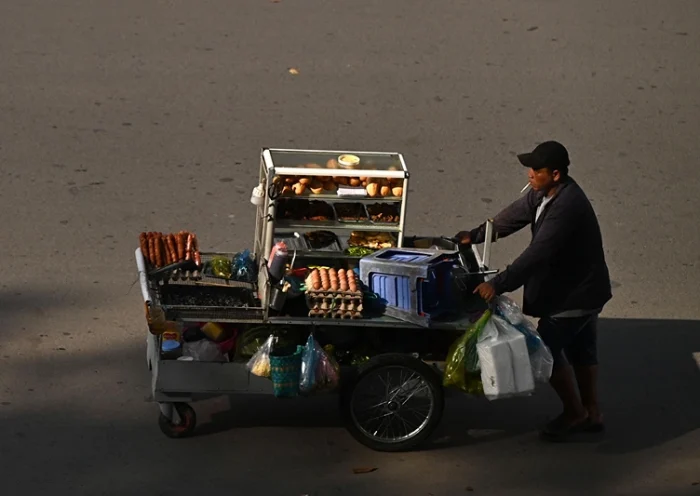 A street vendor pushes his food cart on a street in Can Tho City on October 27, 2023. (Photo by Nhac NGUYEN / AFP) (Photo by NHAC NGUYEN/AFP via Getty Images)
