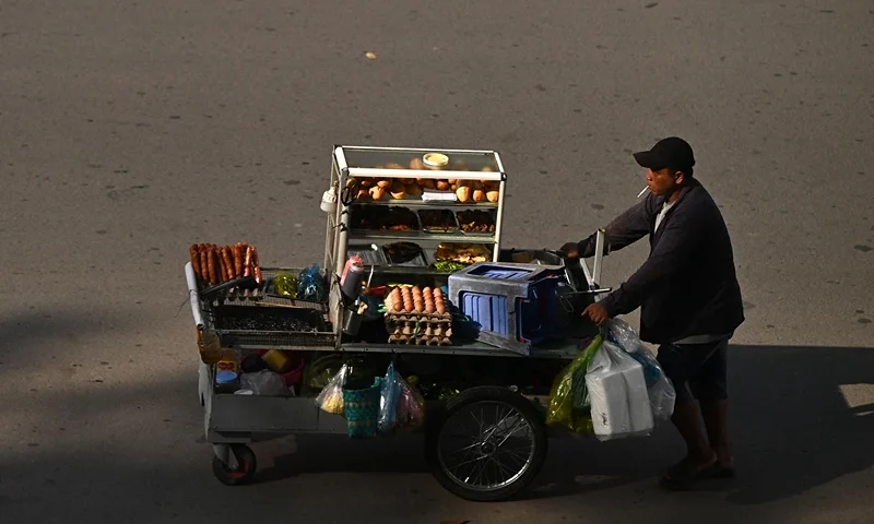A street vendor pushes his food cart on a street in Can Tho City on October 27, 2023. (Photo by Nhac NGUYEN / AFP) (Photo by NHAC NGUYEN/AFP via Getty Images)