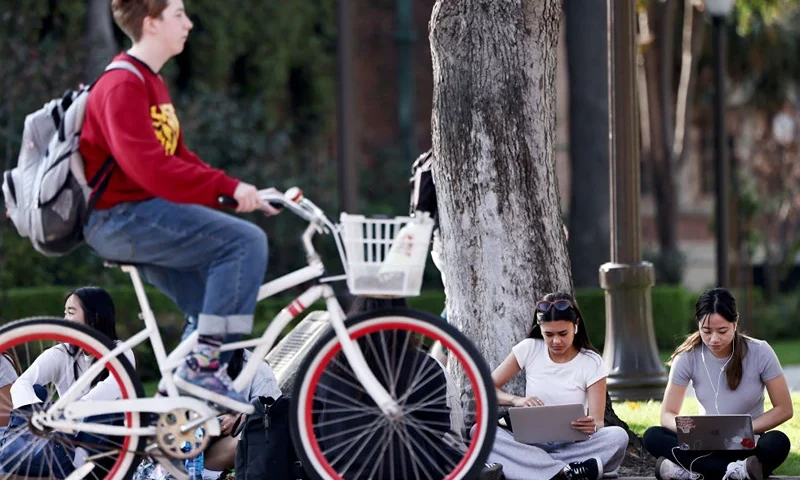 LOS ANGELES, CALIFORNIA - MARCH 21: People gather on the campus of the University of Southern California (USC) on March 21, 2024 in Los Angeles, California. The Biden administration announced today it will forgive $6 billion in student loan debts of 78,000 public service workers. (Photo by Mario Tama/Getty Images)