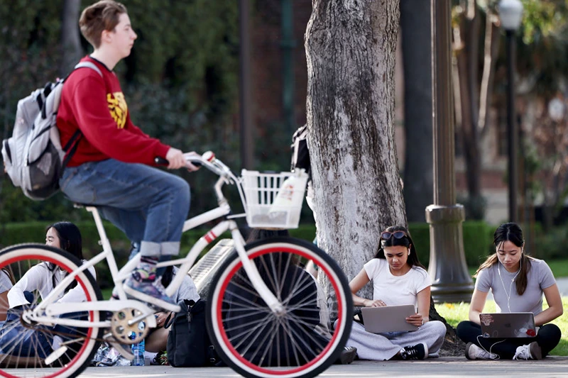 LOS ANGELES, CALIFORNIA - MARCH 21: People gather on the campus of the University of Southern California (USC) on March 21, 2024 in Los Angeles, California. The Biden administration announced today it will forgive $6 billion in student loan debts of 78,000 public service workers. (Photo by Mario Tama/Getty Images)