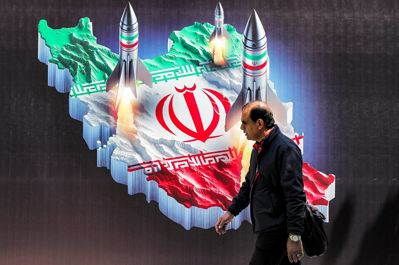 TOPSHOT - A man walks past a banner depicting missiles launching from a representation of the map of Iran coloured with the Iranian flag in central Tehran on April 15, 2024. Iran on April 14 urged Israel not to retaliate militarily to an unprecedented attack overnight, which Tehran presented as a justified response to a deadly strike on its consulate building in Damascus. (Photo by ATTA KENARE / AFP) (Photo by ATTA KENARE/AFP via Getty Images)