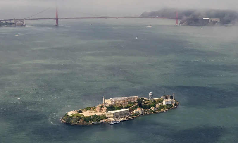 TOPSHOT - An aerial view shows Alcatraz island in front of the Golden Gate Bridge in San Francisco, California on May 16, 2024. Alcatraz Island is 1.25 miles (2.01 km) offshore from San Francisco and initially was a federal prison before being converted into a tourist attraction. The strong currents around the island and cold water temperatures made escape nearly impossible, and the prison became one of the most notorious in American history. (Photo by JOSH EDELSON / AFP) (Photo by JOSH EDELSON/AFP via Getty Images)