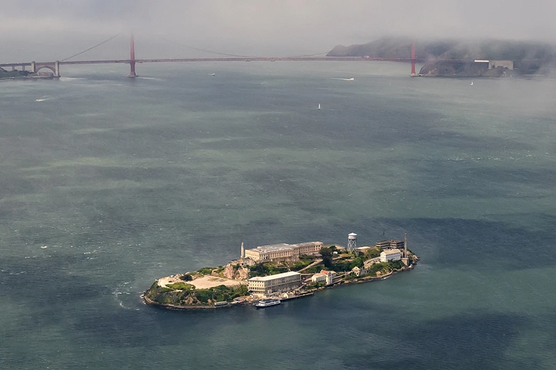 TOPSHOT - An aerial view shows Alcatraz island in front of the Golden Gate Bridge in San Francisco, California on May 16, 2024. Alcatraz Island is 1.25 miles (2.01 km) offshore from San Francisco and initially was a federal prison before being converted into a tourist attraction. The strong currents around the island and cold water temperatures made escape nearly impossible, and the prison became one of the most notorious in American history. (Photo by JOSH EDELSON / AFP) (Photo by JOSH EDELSON/AFP via Getty Images)