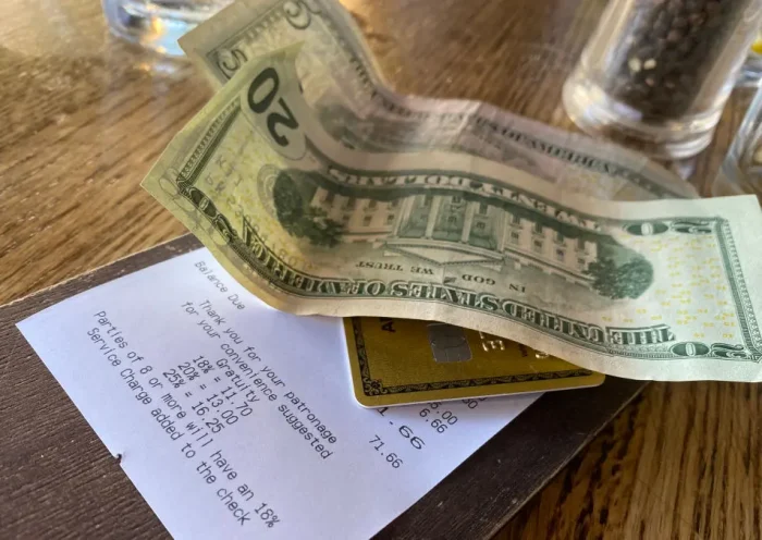 This picture taken on August 24, 2024 shows a bill, with cash for the tip, left on a restaurant table in Los Angeles. Donald Trump and Kamala Harris agree on very little, but the two presidential rivals have found common ground in calling for the elimination of taxes on tips -- a populist move that many criticize as economically irresponsible. Tipping culture in the United States is fundamentally different from most other countries, as customers are encouraged to tip generously on everything from take-out coffee to cocktails. A tip ranging between 15 and 20 percent of the price is considered normal at most restaurants. (Photo by Chris DELMAS / AFP) (Photo by CHRIS DELMAS/AFP via Getty Images)