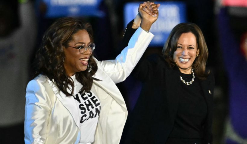 TOPSHOT - US producer and actress Oprah Winfrey (L) holds up US Vice President and Democratic presidential candidate Kamala Harris' hand as she arrive onstage during a campaign rally on the Benjamin Franklin Parkway in Philadelphia, Pennsylvania, on November 4, 2024. (Photo by ANGELA WEISS / AFP) (Photo by ANGELA WEISS/AFP via Getty Images)