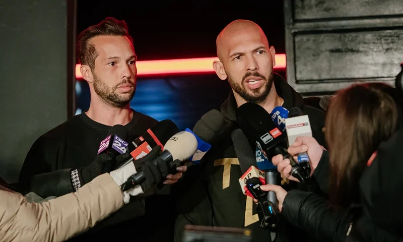 Andrew Tate and his brother Tristan Tate talk to the media outside their residence on March 23, 2025 in Bucharest, Romania. Andrew Tate and his brother Tristan had flown to the United States last month from Romania, where they have been charged with rape, having sex with a minor, human trafficking and money laundering, charges which they deny. Their bail conditions stipulated that they had to return to Romania by March 23. (Photo by Andrei Pungovschi/Getty Images)