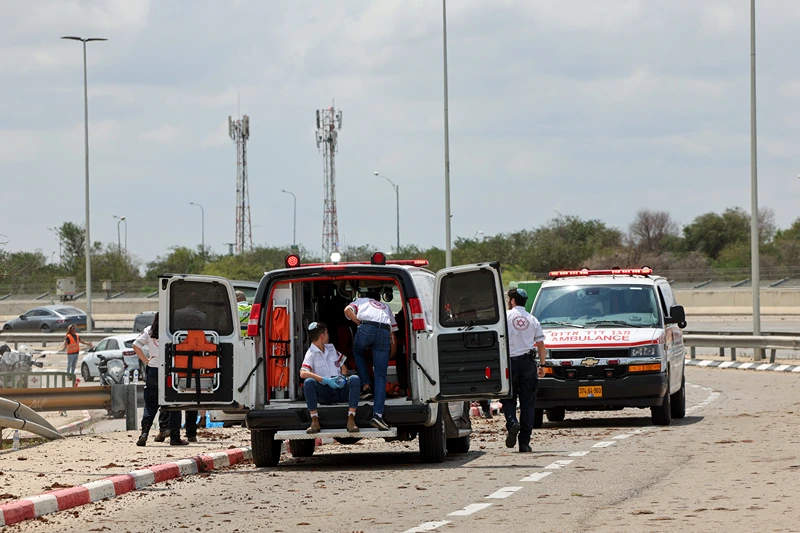 Israeli medical emergency services stand by on a mud-splattered road outside Israel's Ben Gurion airport after a missile struck near the facility on May 4, 2025. A missile launched from Yemen struck near Israel's main international airport on May 4, Israeli authorities said, an attack that briefly halted air traffic and triggered threats of retaliation. (Photo by Jack GUEZ / AFP) (Photo by JACK GUEZ/AFP via Getty Images)