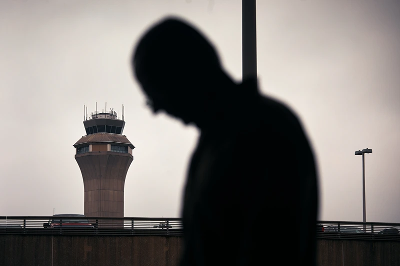 NEWARK, NEW JERSEY - MAY 6: A man stands outside Terminal C with the airport control tower in the background at Newark Liberty International Airport, on May 6, 2025 in Newark, New Jersey. Passengers traveling to, from, or through Newark Liberty International Airport (EWR) have experienced several days of delays and cancellations caused by air traffic control staffing shortages and equipment malfunctions.(Photo by Andres Kudacki/Getty Images)