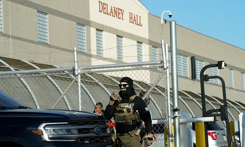Immigration and Customs Enforcement (ICE) agents stand near a gate as they watch protestors at a demonstration in Elizabeth, New Jersey May 7, 2025, outside Delaney Hall, a newly converted immigrant detention centre. Delaney Hall has the ability to hold over a 1000 people, and the detention facility, privately owned by The GEO Group, holds a contract with the federal government to house people arrested by ICE. (Photo by TIMOTHY A. CLARY / AFP) (Photo by TIMOTHY A. CLARY/AFP via Getty Images)