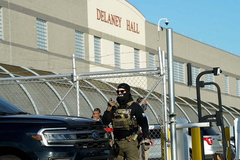 Immigration and Customs Enforcement (ICE) agents stand near a gate as they watch protestors at a demonstration in Elizabeth, New Jersey May 7, 2025, outside Delaney Hall, a newly converted immigrant detention centre. Delaney Hall has the ability to hold over a 1000 people, and the detention facility, privately owned by The GEO Group, holds a contract with the federal government to house people arrested by ICE. (Photo by TIMOTHY A. CLARY / AFP) (Photo by TIMOTHY A. CLARY/AFP via Getty Images)